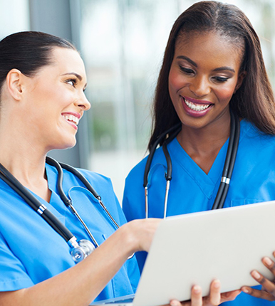 smiling nurses looking at laptop